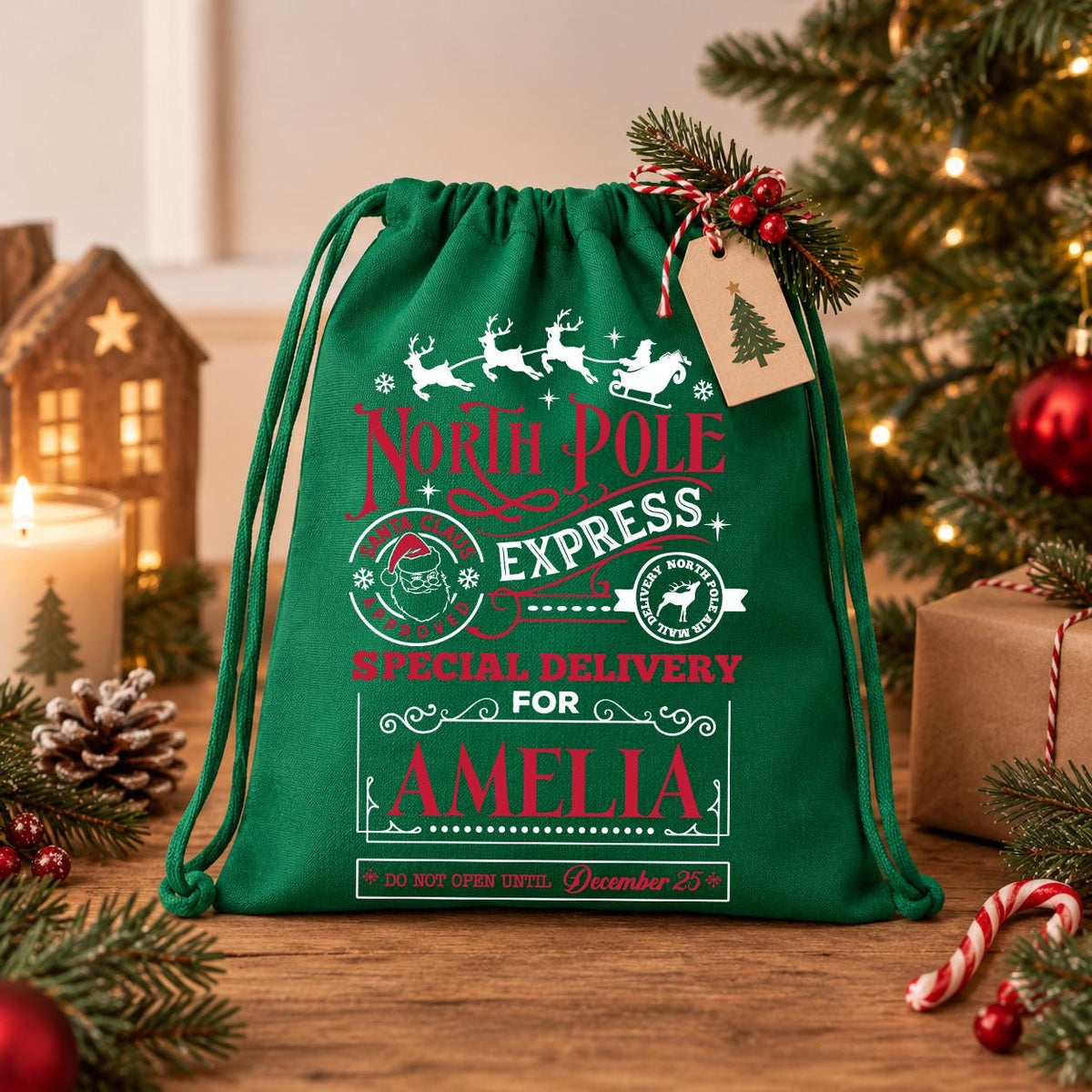 A green drawstring bag with a Christmas-themed design, featuring text and illustrations related to the North Pole Express special delivery service. The bag is placed on a wooden surface, surrounded by holiday decorations such as a Christmas tree, ornaments, and a candle.